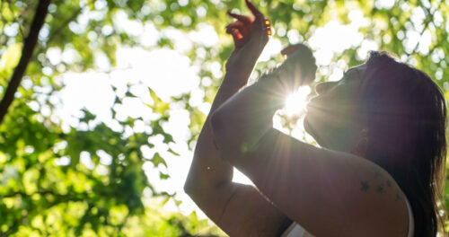 Lightworker Audrey Love practices light language with sun beaming through trees